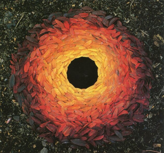 Leaf sculpture by Andy Goldsworthy showing a circular arrangement of red and orange leaves around a dark centre